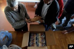A volunteer delivers bread and other supplies to homeless persons at the ''Shelter of Love and Solidarity'' in central Athens, April 25, 2017.