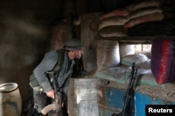 A rebel fighter looks out through sandbags on the forth day of the truce, on al-Rayhan village front near the rebel held besieged city of Douma, in the eastern Damascus suburb of Ghouta, Syria, Jan. 2, 2017.