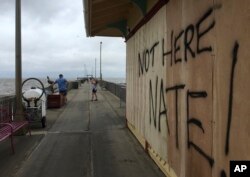 People shoot photos near a sign on the Shux on the Pier restaurant in Fairhope, Alabama, Oct. 8, 2017.