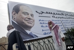Egyptian men walk past a campaign billboard of Egyptian ex-army chief and leading presidential candidate Abdel Fattah el-Sissi on a pedestrian bridge in Fayyum, some 100 kilometres south of Cairo, May 20, 2014.