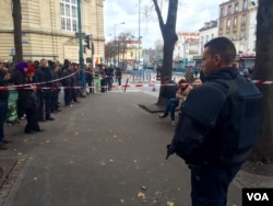 Crowd at standoff as riot policeman watches in Saint-Denis, Paris, Nov. 18, 2015. (D. Schearf/VOA)