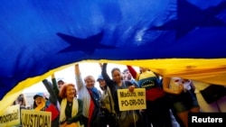 People reacts as they wave a Venezuelan flag during a protest in support of Venezuelan opposition leader Juan Guaido at Colon Square in Madrid, Spain, May 1, 2019.