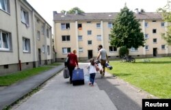FILE - Lilas, a 4-year-old-refugee from Syria, and her parents walk to their refugee home in Muelheim an der Ruhr, Germany, after receiving articles for daily use prepared by donors at a distribution center on Aug, 20, 2015.