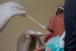 Seorang pekerja sedang melakukan tes usap Covid-19 terhadap seorang perempuan di Jakarta, 30 April 2020. (Foto: Reuters)