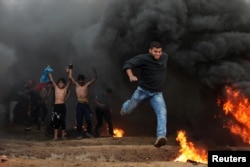 A Palestinian demonstrator runs during a protest calling for lifting the blockade on Gaza, at the Israel-Gaza border fence in Gaza, Oct. 26, 2018.