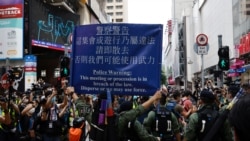 资料照：香港警察对在中国国庆日要求北京政府释放12港人的抗议者展示警示牌。（2020年10月1日）