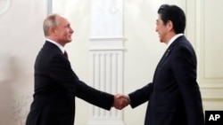 Russian President Vladimir Putin, left, and Japanese Prime Minister Shinzo Abe shake hands before an opening ceremony of the cross-cultural year of Russia and Japan at the Bolshoi Theater in Moscow, Russia, May 26, 2018.
