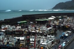 Kapal nelayan merapat di pelabuhan Daxi, Yilan saat ombak (belakang) menghantam pantai akibat angin kencang yang dipicu Topan In-Fa, mendekati pantai timur laut Taiwan, 23 Juli 2021. (Foto oleh Sam Yeh / AFP)