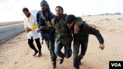 Pemberontak Libya mengangkat seorang rekan mereka yang cedera akibat serangan pasukan Gadhafi di Ras Lanuf, Kamis (10/3).