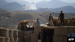 Arhiva - Avganistanski lokalni policajci gledaju kako se uzdiže dim sa mesta vazdušnog udara na pozicije Islamske države, na kontrolnom punktu u istočnoj provinciji Nangarhar, 7. jula 2018.