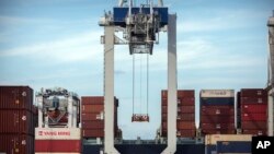 FILE - A ship-to-shore crane prepares to load a 40-foot shipping container onto a container ship at the Port of Savannah in Savannah, Georgia, July 5, 2018.