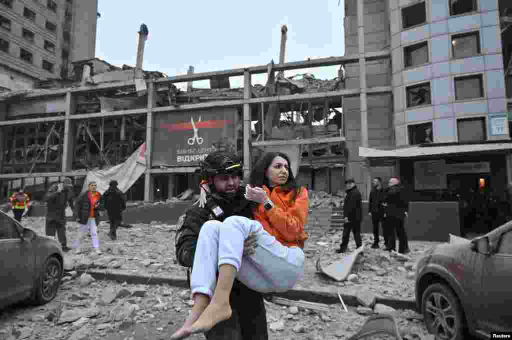 A police officer evacuates a woman from a building heavily damaged by a Russian missile strike in Zaporizhzhia, Ukraine.