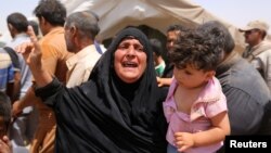 A women who fled Ramadi holds a child in a camp in the town of Amiriyat al-Fallujah, west of Baghdad, Iraq, May 22, 2015. 