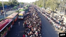 FILE - Migrant workers and their families line up in a New Delhi bus terminal to leave for their villages during a government-imposed nationwide lockdown as a preventive measure against the coronavirus, March 28, 2020.