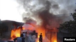 Residents try to extinguish damaged buildings on fire after what activists said was shelling by forces loyal to Syria's President Bashar al-Assad in Erbeen, near Damascus, October 18, 2012. 