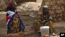 Village girls watch from a broken wall as local health workers remove earth contaminated by lead from a family compound in the village of Dareta in Gusau, Nigeria, June 10, 2010. 