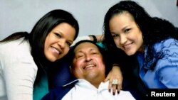 Presiden Venezuela Hugo Chavez berbaring di atas tempat tidur di rumah sakit dan tersenyum diantara kedua putrinya Rosa Virginia (kanan) dan Maria pasca operasi kanker di Havana, 15 Februari 2013 (Foto: dok). Foto ini merupakan foto pertama sejak Presiden Chavez menjalani pengobatan di Kuba, Desember lalu.