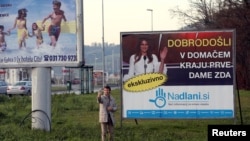 FILE - A man takes a selfie in front of placard with a picture of Melania Trump in her hometown Sevnica, Slovenia, Dec. 1, 2016. Banner reads 'Welcome in hometown of first lady of U.S.' 