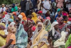 FILE - Families wait outside the port of Pemba on April 1, 2021, for the boat of evacuees from Palma.