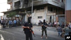 Des membres de la garde de sécurité du Hamas devant un immeuble touché par un explosif à Gaza, 19 juillet 2015.