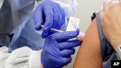FILE - A patient receives a shot in clinical trial of a potential vaccine for COVID-19, the disease caused by the new coronavirus, Monday, March 16, 2020, at the Kaiser Permanente Washington Health Research Institute in Seattle. (AP Photo/Ted S. Warren)