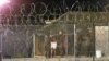 FILE - Marines at Camp X-Ray at the Naval Base at Guantanamo Bay, Cuba escort a newly arriving detainee into a processing tent after being showered.