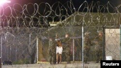Des soldats au camp X-Ray sur la base de Guantanamo Bay à Cuba escortent un détenu peu après son arrivée, le 7 février 2002.