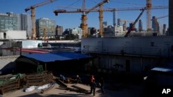 Sejumlah pekerja konstruksi tampak berada di dekat lokasi pembangunan sebuah proyek di area pusat bisnis di Beijing, China, pada 11 Oktober 2021. (Foto: AP/Ng Han Guan)