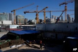 Workers labor near a construction site with cranes near the central business district skyline in Beijing, China, Monday, Oct. 11, 2021. (AP Photo/Ng Han Guan)