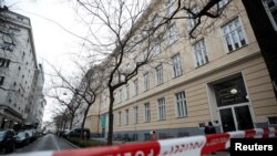 FILE - Policemen guard the entrance of a school after authorities put it under isolation because of suspicions of a coronavirus case, in Vienna, Austria Feb. 26, 2020. Austria shut all of its schools early in the coronavirus outbreak.