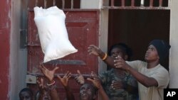 Men catch a bag of rice as they unload a government food distribution, in a small section of the flooded Delmas neighborhood in Port-au-Prince, Haiti, Oct. 18, 2019. 