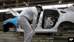 FILE - In this April 8, 2020, photo, employees work on a car assembly line at the Dongfeng Honda Automobile Co., Ltd factory in Wuhan in central China's Hubei province. 