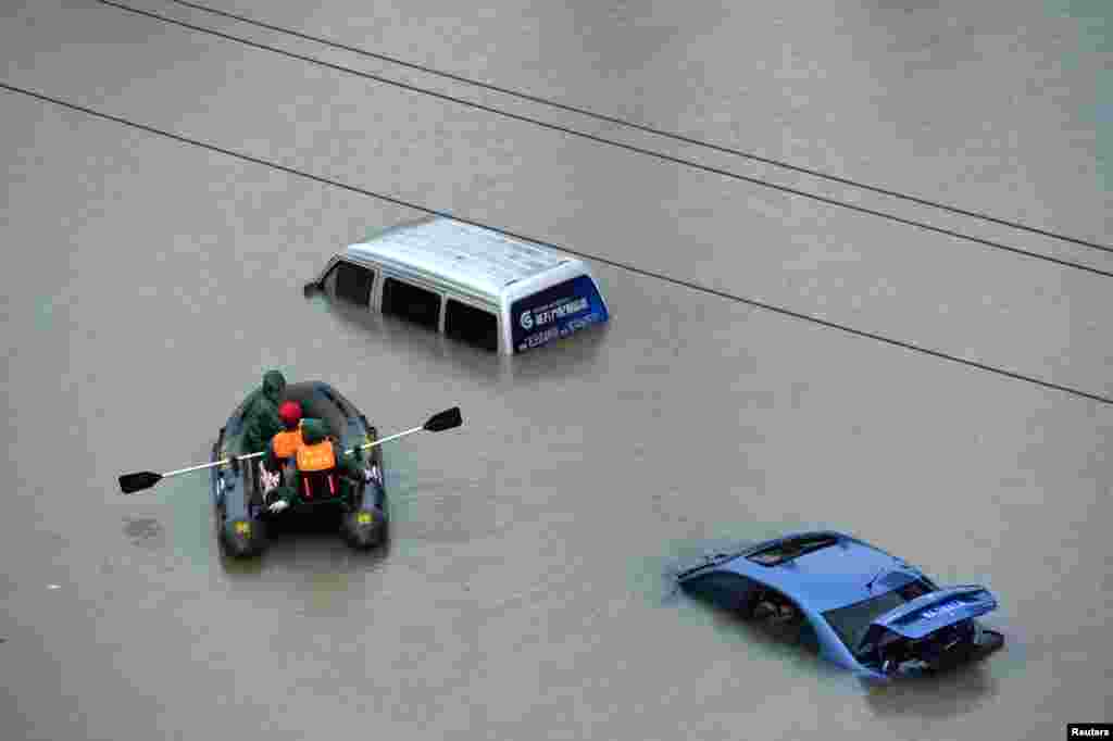 A rescue boat approaches a submerged car on a flooded street after heavy rainfall in Guiyang city, Guizhou province, China.