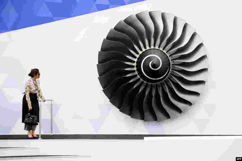 Seorang perempuan berdiri di dekat model mesin pesawat Rolls Royce pada pameran udara Farnborough di Inggris.