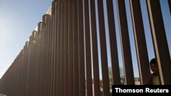 FILE - A child looks through the bars of a wall from the side of Ciudad Juarez, Mexico, in this picture taken on the side of El Paso, Texas, U.S.A., May, 25, 2019.