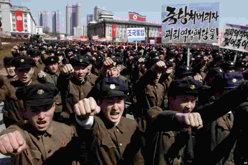 Para mahasiswa mengepalkan tangan ke udara saat berbaris melalui Alun-Alun Kim Il Sung di tengah kota Pyongyang, Korea Utara (29/3). (AP/Jon Chol Jin)