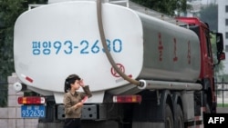 Seorang petugas pompa bensin melewati truk yang membawa bahan bakar di Pyongyang. Korea Utara (foto: ilustrasi). 