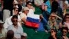 Penonton yang memegang bendera Rusia menyaksikan pertandingan putaran ketiga tunggal putra antara Daniil Medvedev dari Rusia dan Marin Cilic dari Kroasia di London, Sabtu 3 Juli 2021. (Foto: AP)