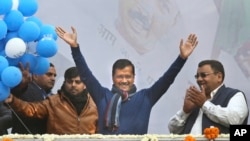 Incumbent Delhi Chief Minister Arvind Kejriwal, center, waves at Aam Aadmi Party, or "common man's" party headquarters as they celebrate the party's victory in New Delhi, India, Feb. 11, 2020. 