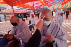 A Buddhist monk wearing a face mask is checked his temperature by a Korea Red Cross official to donate blood due to the shortage of blood donators amid the rapid spread of the new coronavirus at the Jogyesa temple in Seoul, March 24, 2020.