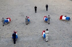 FILE - French President Emmanuel Macron pays his respect in front of the flag-draped coffins of the thirteen French soldiers killed in Mali, during a ceremony at the Hotel National des Invalides in Paris, Dec. 2, 2019.