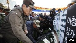 Veteran Angkatan Darat Korea Selatan meletakkan bunga di depan spanduk bergambar penjaga pantai Lee Cheong-ho saat protes anti-Tiongkok depan Kedutaan Tiongkok diSeoul (13/12).