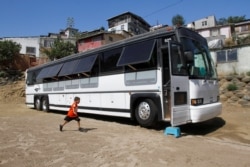 A migrant child runs towards a bus converted in a classroom as part of Schools On Wheels program by California's 'Yes We Can' organization, in Tijuana, Mexico, Aug. 2, 2019.