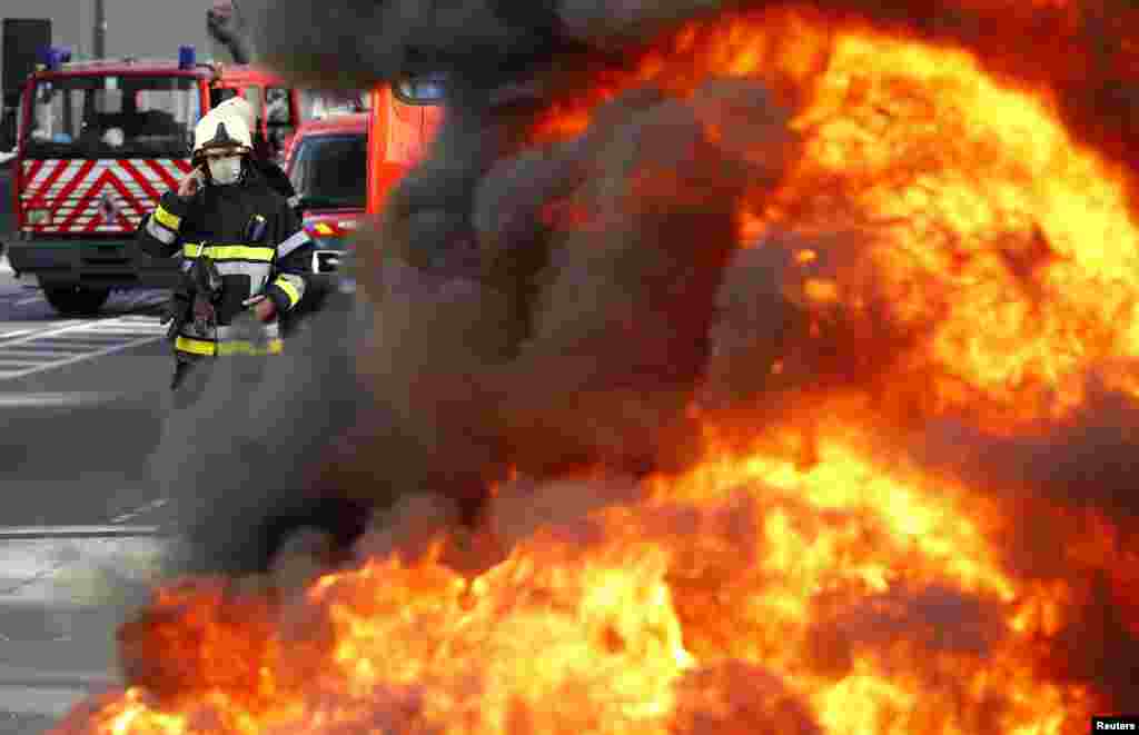 Seorang petugas pemadam kebakaran Belgia berdiri di belakang ban yang dibakar oleh rekan-rekannya, para pemadam kebakaran yang tengah melakukan protes menuntut kondisi kerja yang lebih baik di kota Brussels. 