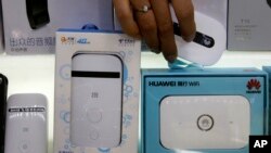 A worker takes a Huawei mobile Internet device next to it competitor ZTE Corp, left, which are displayed for sale at a computer mall in Beijing Wednesday, July 4, 2018. 