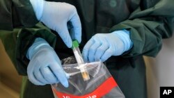 Two nurses demonstrate taking a sample for a coronavirus test at the infection station of the university hospital in Essen, Germany, March 12, 2020. 