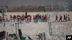 Migranti stoje američkog graničnog zida nakon što su ih zadržale američke imigracione vlasti, 27. decembar 2023.