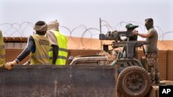 Les commandos de la force française Barkhane montent une mitrailleuse sur une camionnette camouflée alors que des travailleurs maliens passent avant de partir en mission depuis leur base de Gao, au Mali, le undi 7 juin 2021.