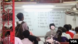 រូបឯកសារ៖ សិស្ស​ម្នាក់​កំពុង​អាន​ពាក្យ​និង​បក​ប្រែ​ពាក្យ​ឲ្យ​គ្រូ​និង​សិស្ស​ដទៃ​ទៀត​ស្តាប់​នៅ​ក្នុង​ថ្នាក់​រៀន​ភាសា​អង់គ្លេស​តាម​ផ្ទះ​មួយ​កន្លែង​​នៅ​ខាង​ក្រោយ​វិទ្យាល័យ​បាក់ទូក​ក្រុង​ភ្នំពេញ កាល​ពី​ថ្ងៃទី១៧ ខែកក្កដា ឆ្នាំ២០១៥។ (ស៊ូ ពិសែន/VOA)