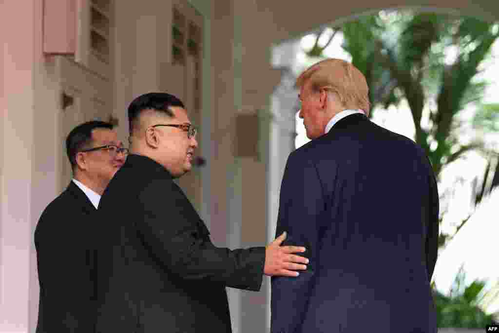 Pemimpin Korea Utara Kim Jong Un (tengah) menyambut Presiden Amerika Serikat Donald Trump (kanan) pada awal acara pertemuan bersejarah antara Amerika Serikat dan Korea Utara di Hotel Capella, Pulau Sentosa, Singapura. (Foto:AFP)
